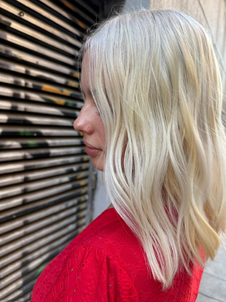 Rubio platino de perfil con ondas suaves, decoloración en ATICA Salón Malasaña